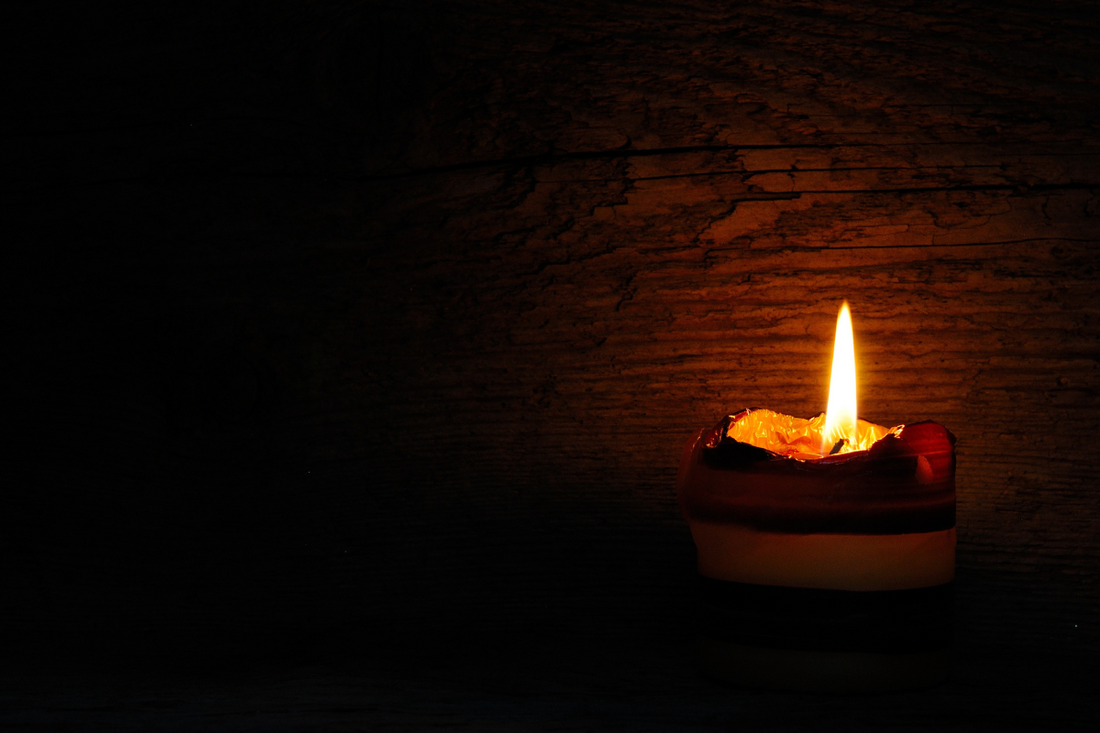 A single candle glowing warmly in the dark, creating a serene and reflective atmosphere.